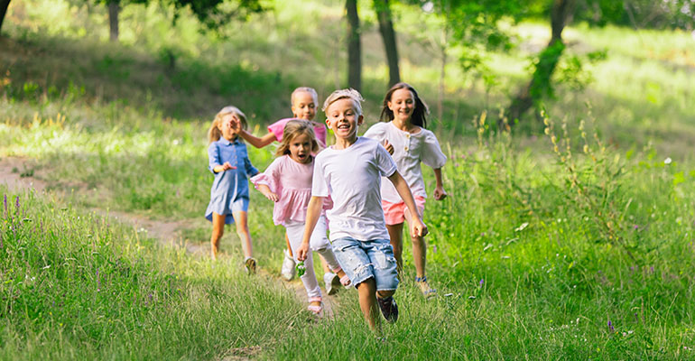 Barn som springer på ett grönskande fält.