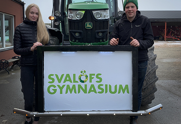 Lantbrukseleverna Johanna Martinsson som tagit initiativ till traktorveckan och Axel Jönsson, som svetsat skylten är redo för traktorvecka. Foto: Åsa Meierkord
